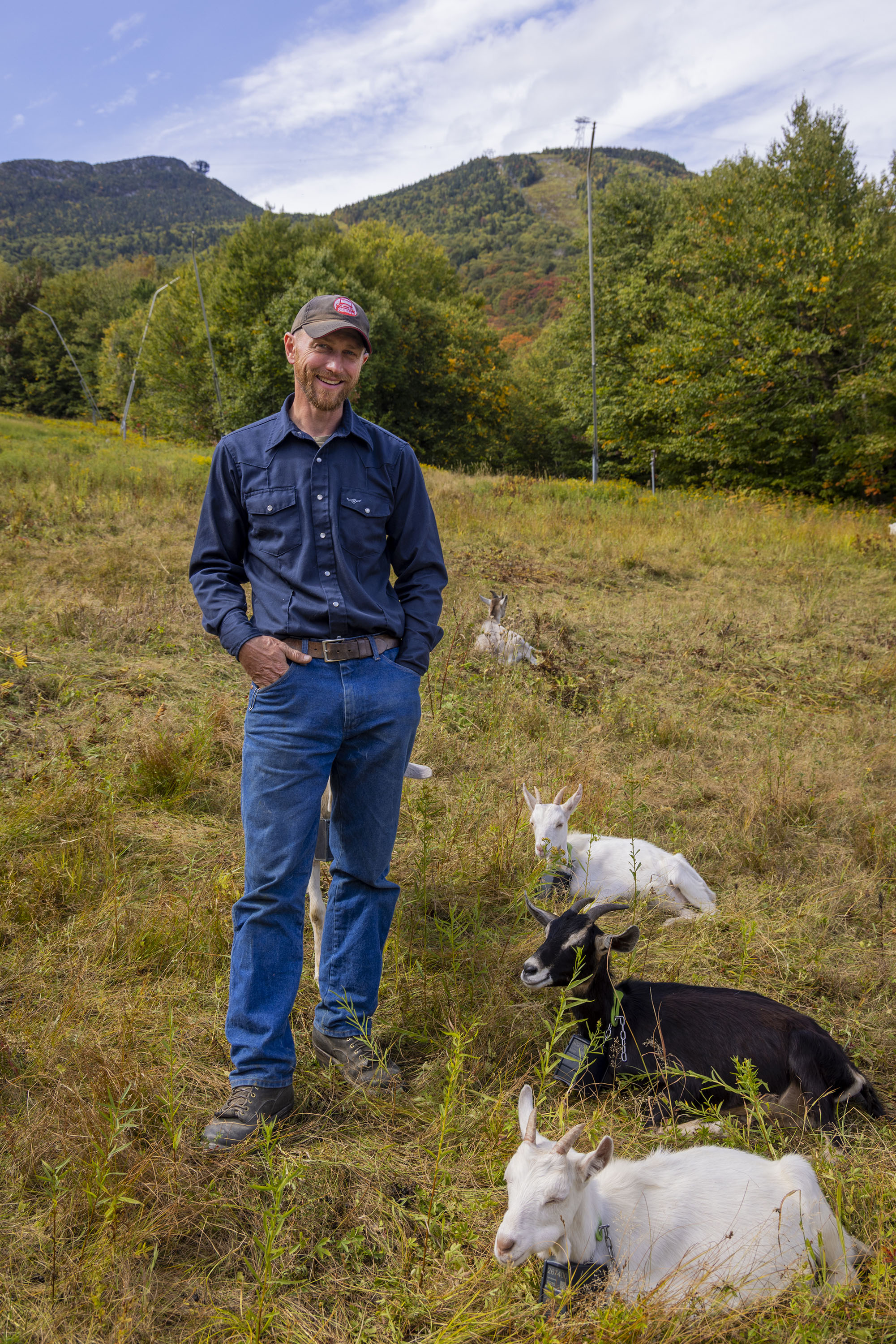 Farmer standing on on the mountain with goats