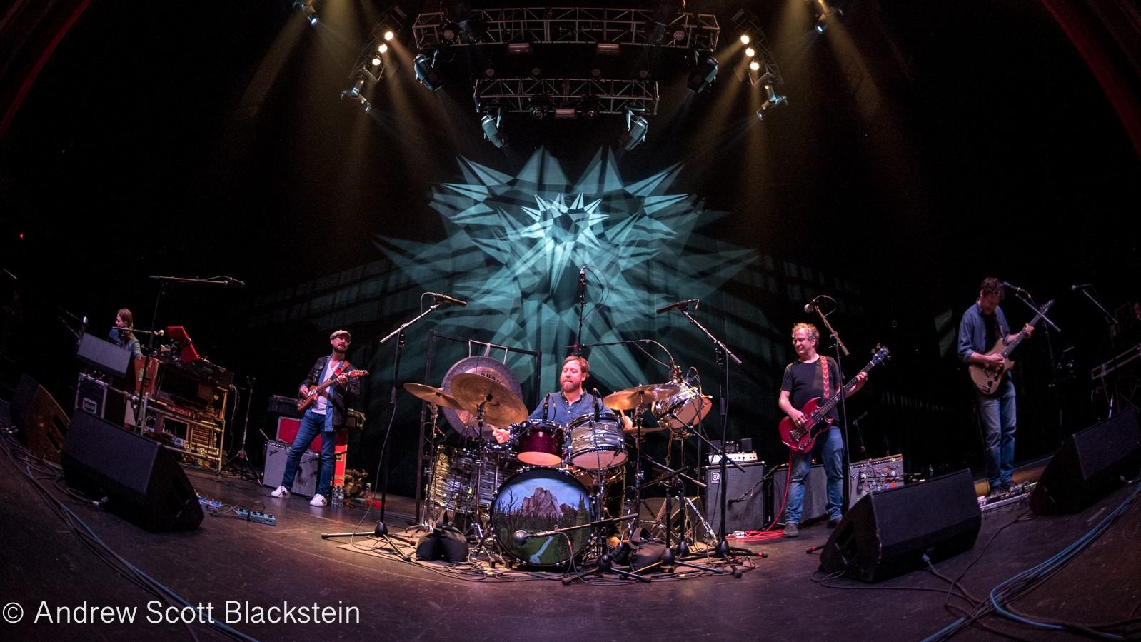 Photo of band playing Cream Puff War on stage with colored lights