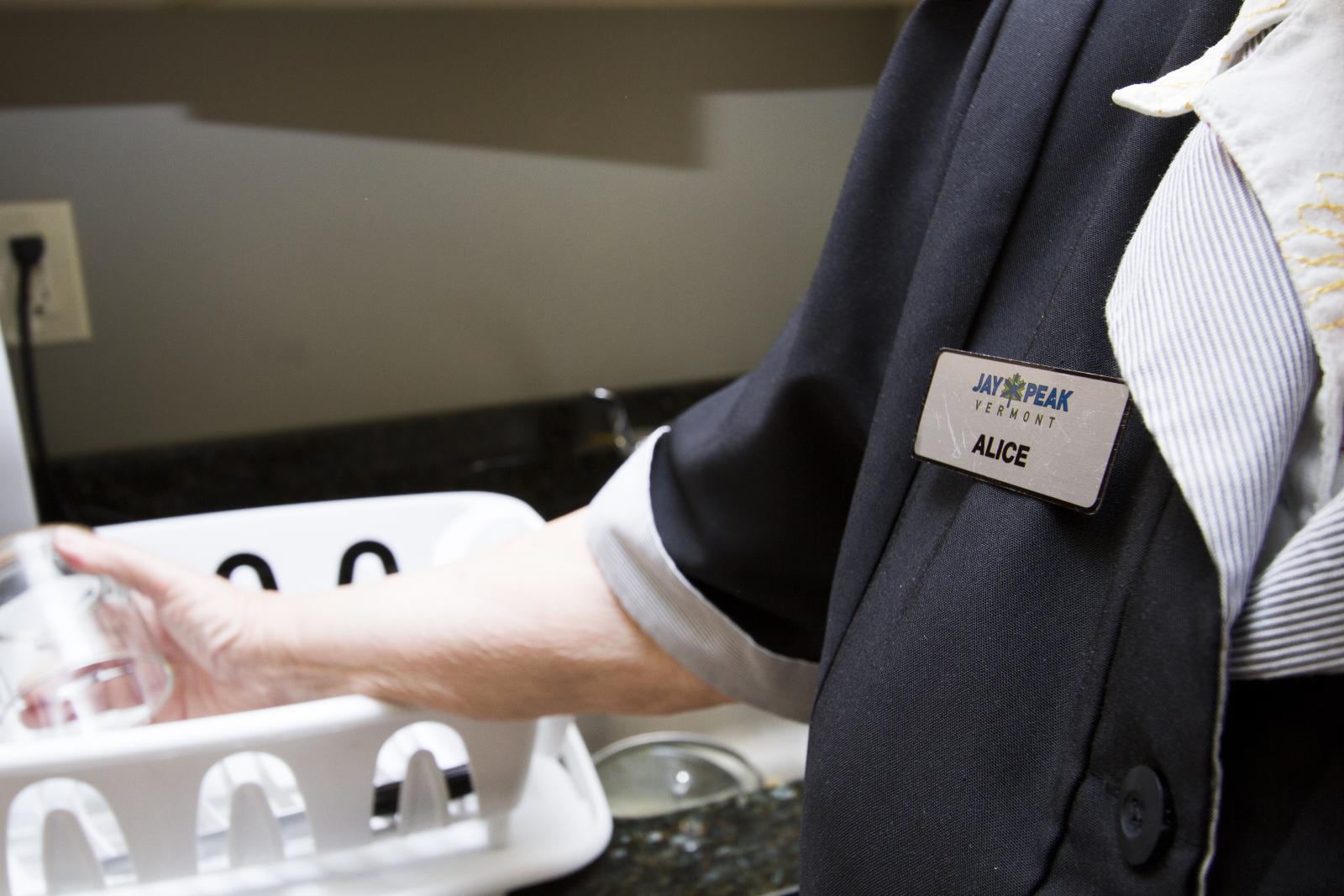 close-up of alice washing a cup, with her Jay Peak nametag visible