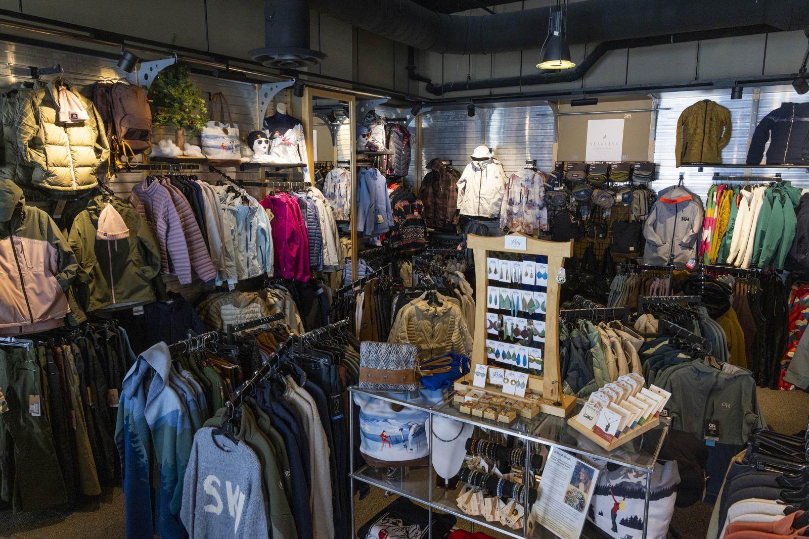 Clothing store interior with racks of jackets and shirts, warm lighting.