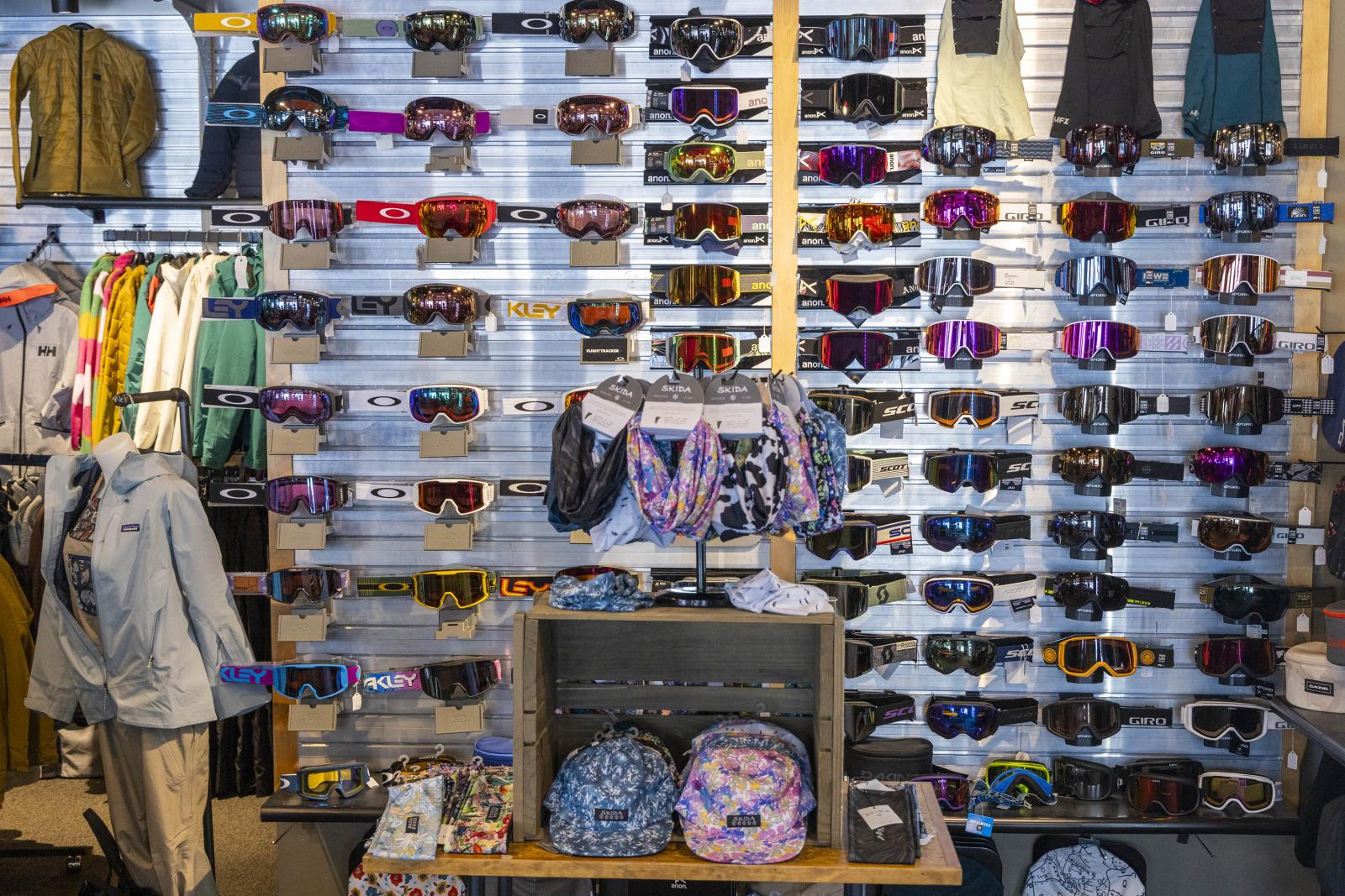 Sunglasses display with colorful bands and backpacks on shelves.