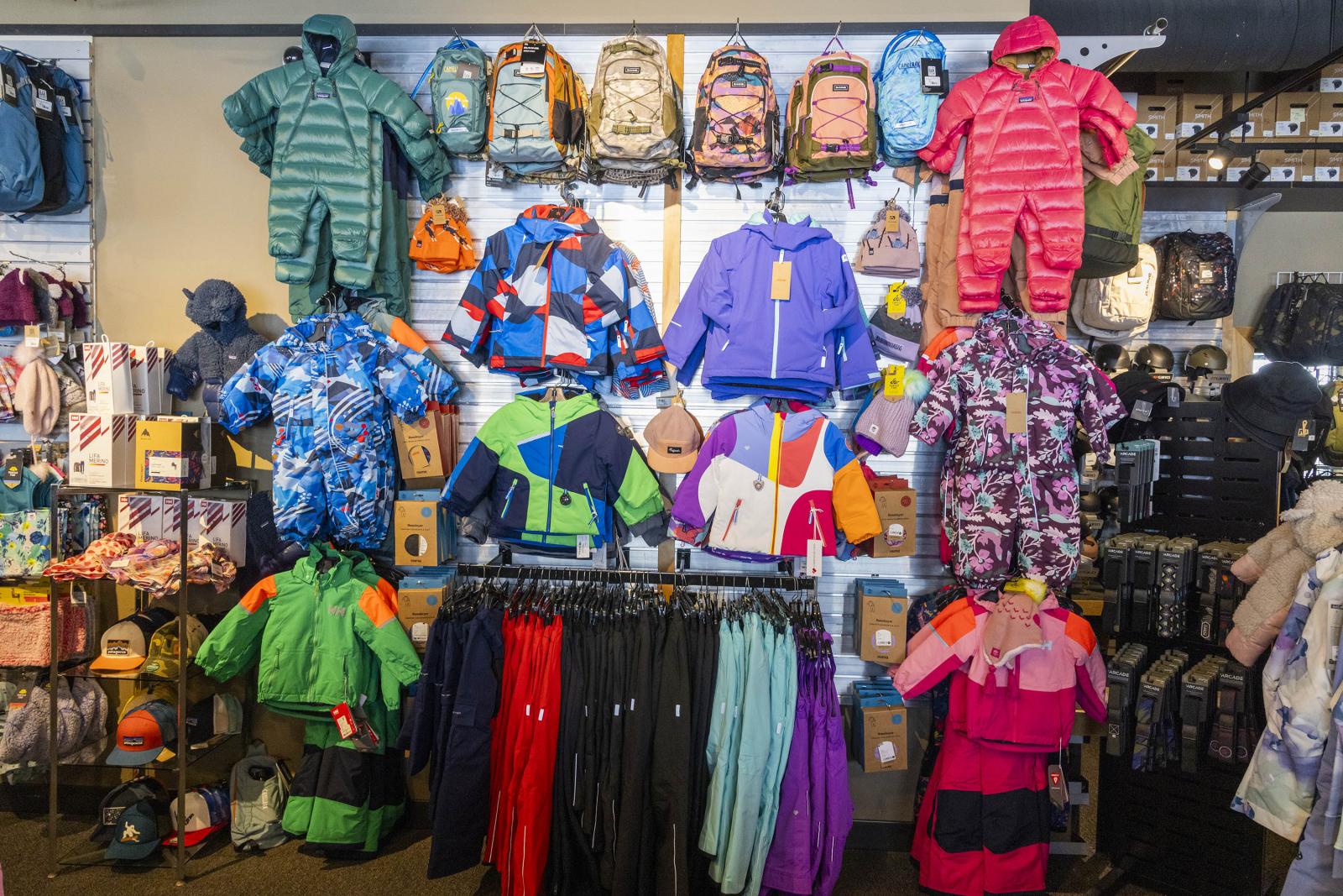 Kids' colorful winter gear displayed on a store wall.