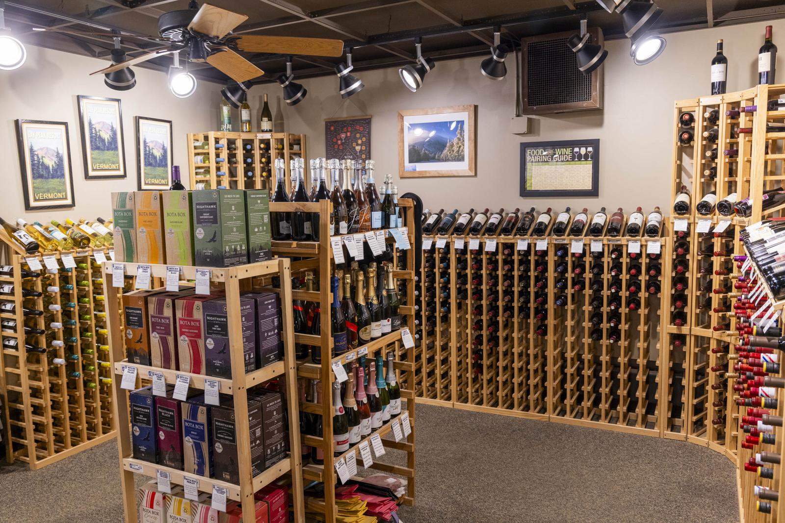 Wine store with shelves of various bottles, framed pictures on the walls.