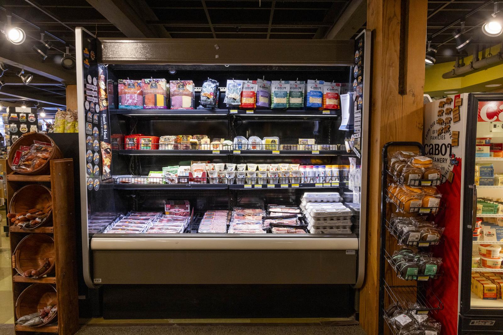 Grocery store refrigerated section with various packaged meats and cheeses.