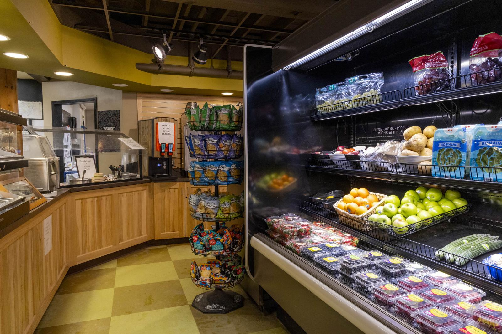 Grocery store produce section with fruits and vegetables on shelves.