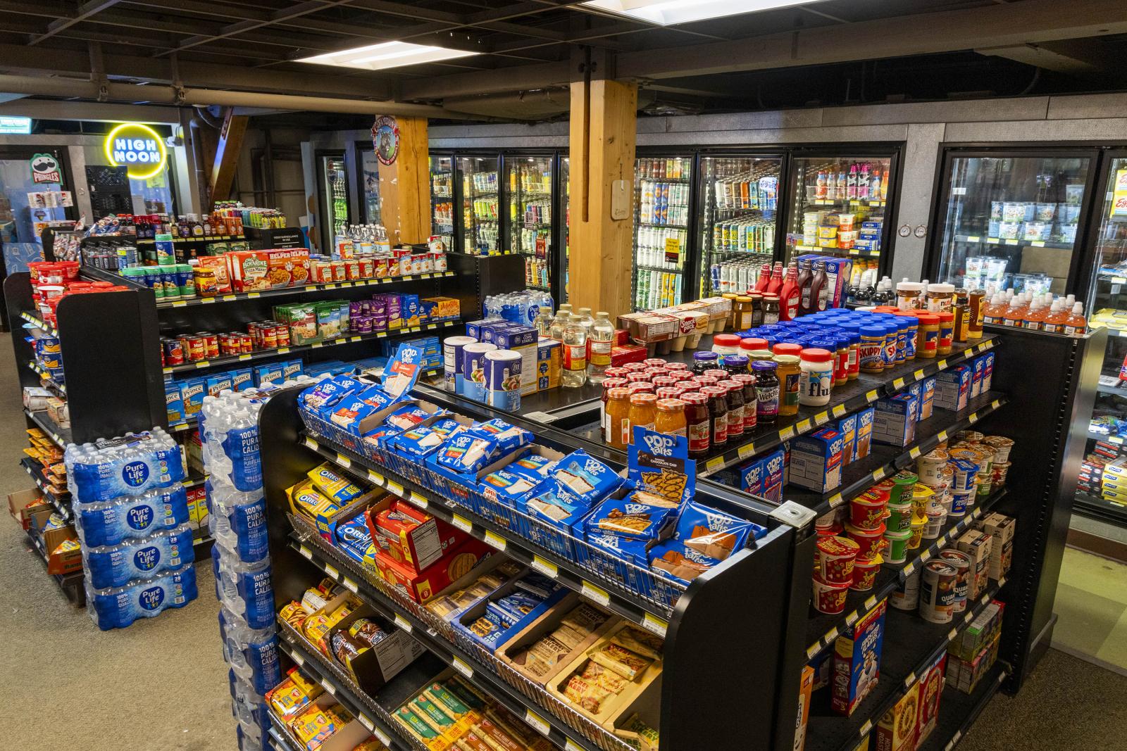 Convenience store interior with colorful snack shelves and refrigerators.