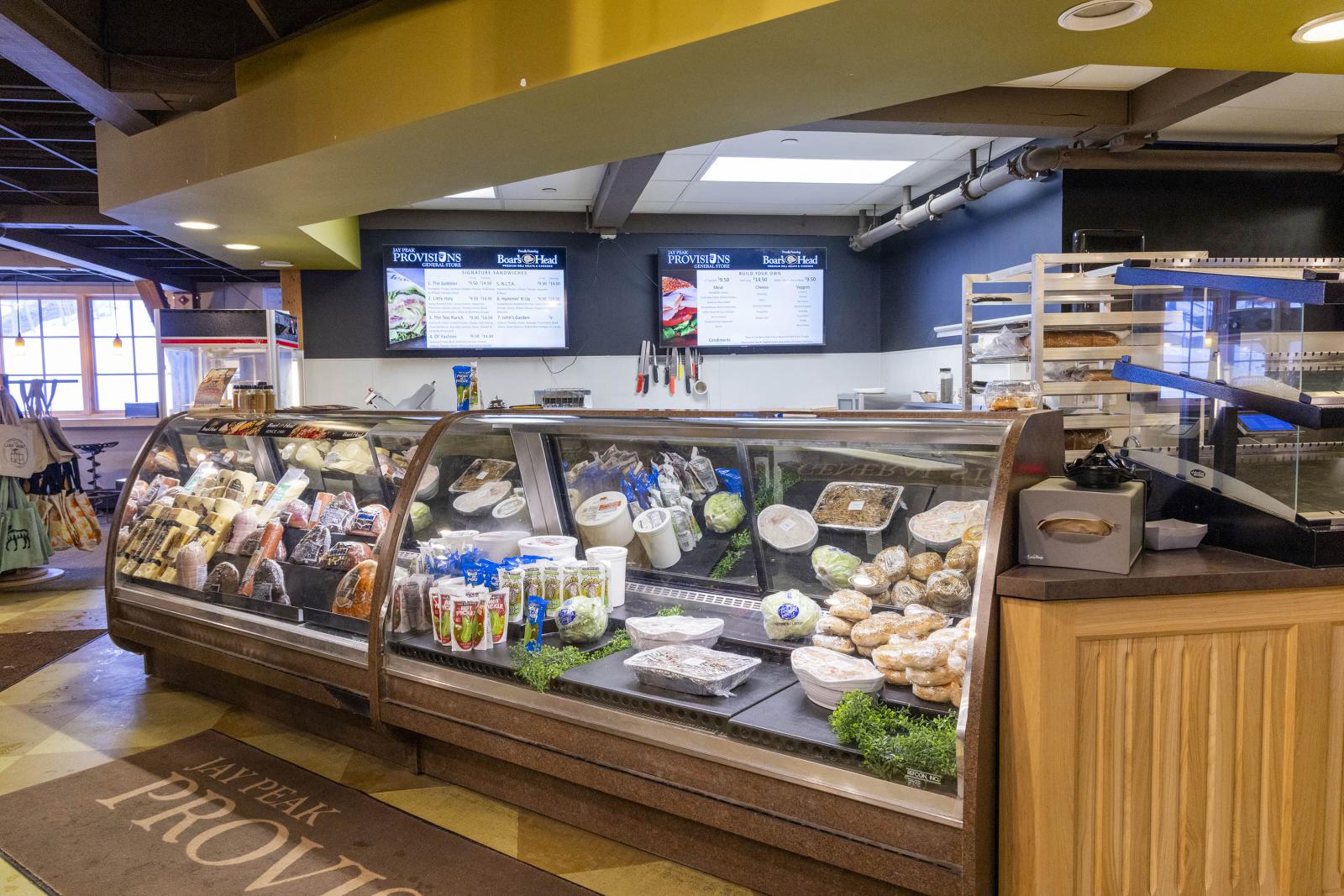 Deli counter with sandwiches, salads, and baked goods under display lights.