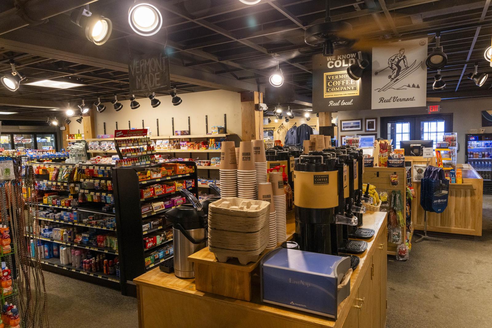 Coffee shop interior with shelves of snacks and a coffee station.