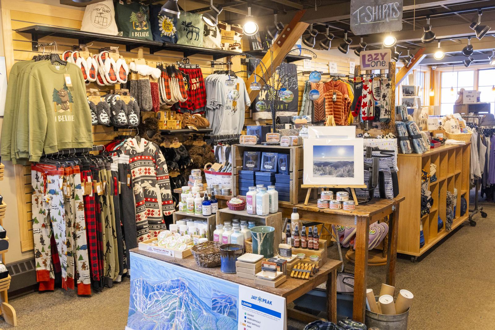 Cozy store with clothing, mugs, and framed art on display. Warm lighting enhances the setting.