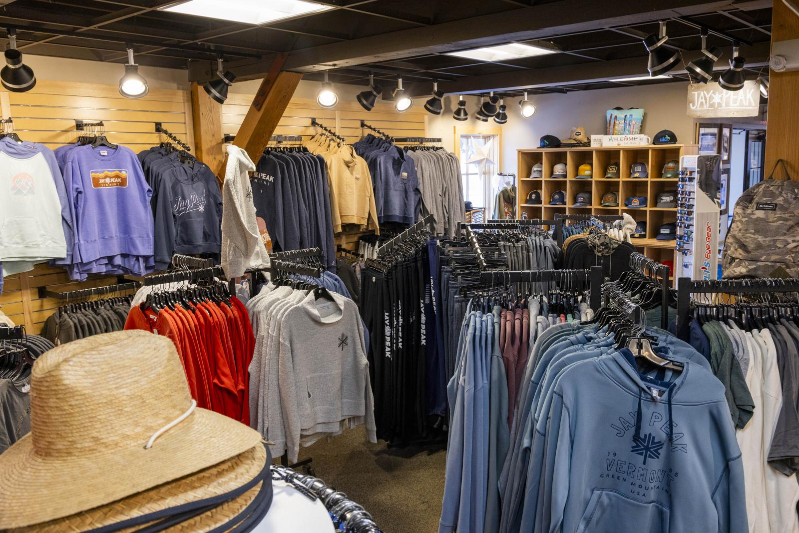 Clothing store interior with racks of shirts and hats under bright lighting.