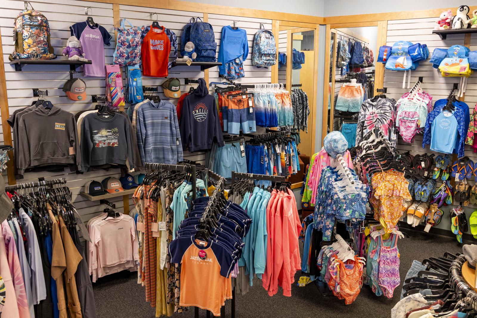 Clothing store with colorful apparel and accessories neatly displayed on racks and shelves.