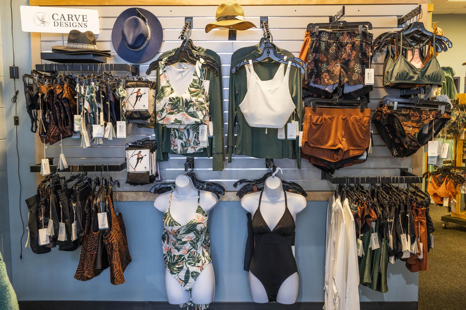 Swimwear display with various bikinis, swimsuits, and hats on hangers.
