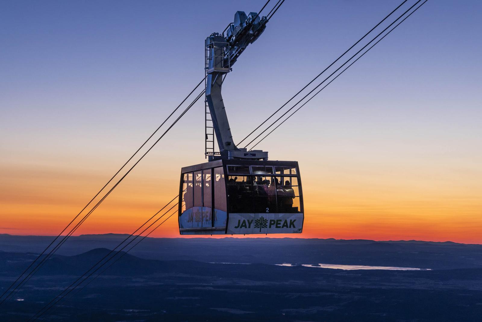 Aerial Tram against a colorful sunrise sky above mountainous landscape.