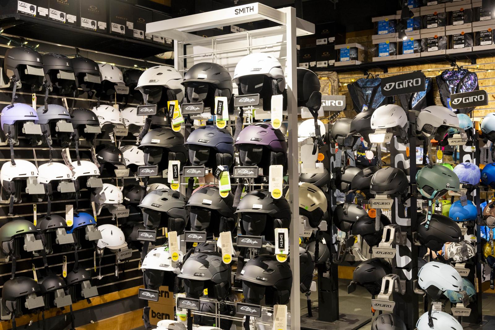 Store display with various bike helmets in black, white, and colorful options.
