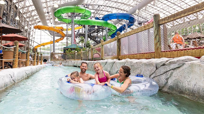 Family enjoying a lazy river ride at an indoor water park.