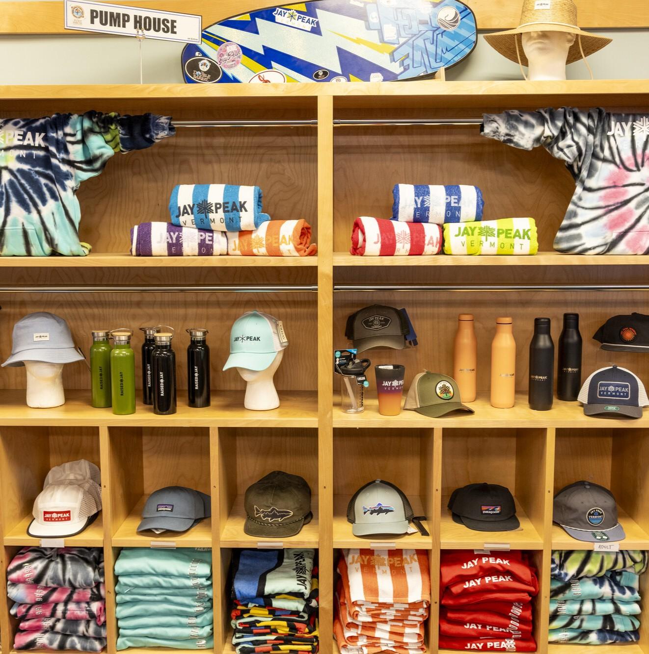 Store display with tie-dye shirts, towels, bottles, hats, and folded clothes.