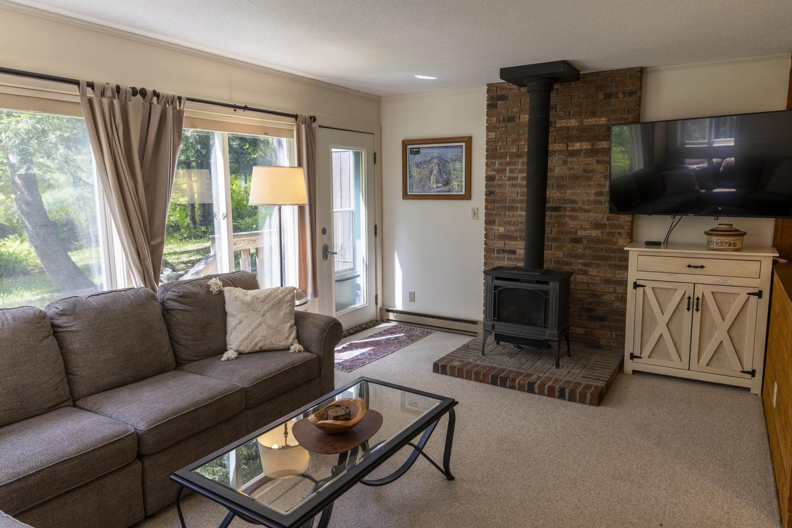 Cozy living room with a sofa, fireplace, TV, and large window.