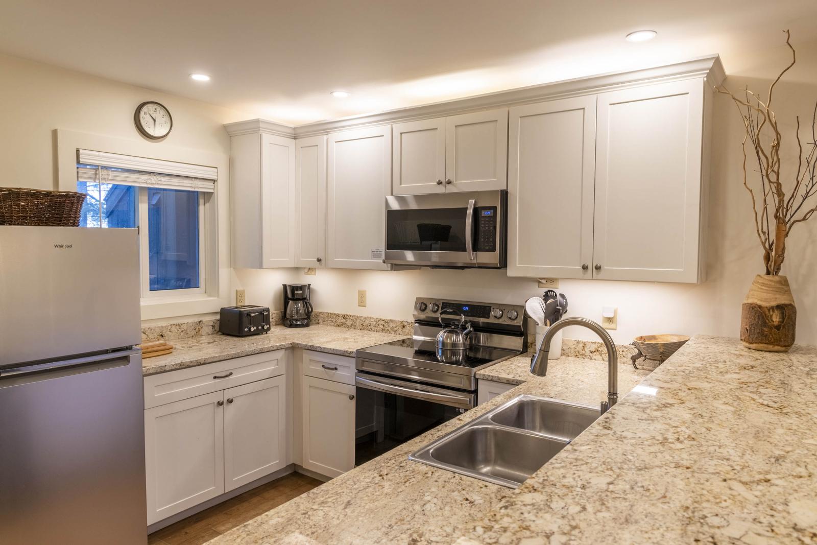 Modern kitchen with granite countertops, stainless steel appliances, and white cabinets.