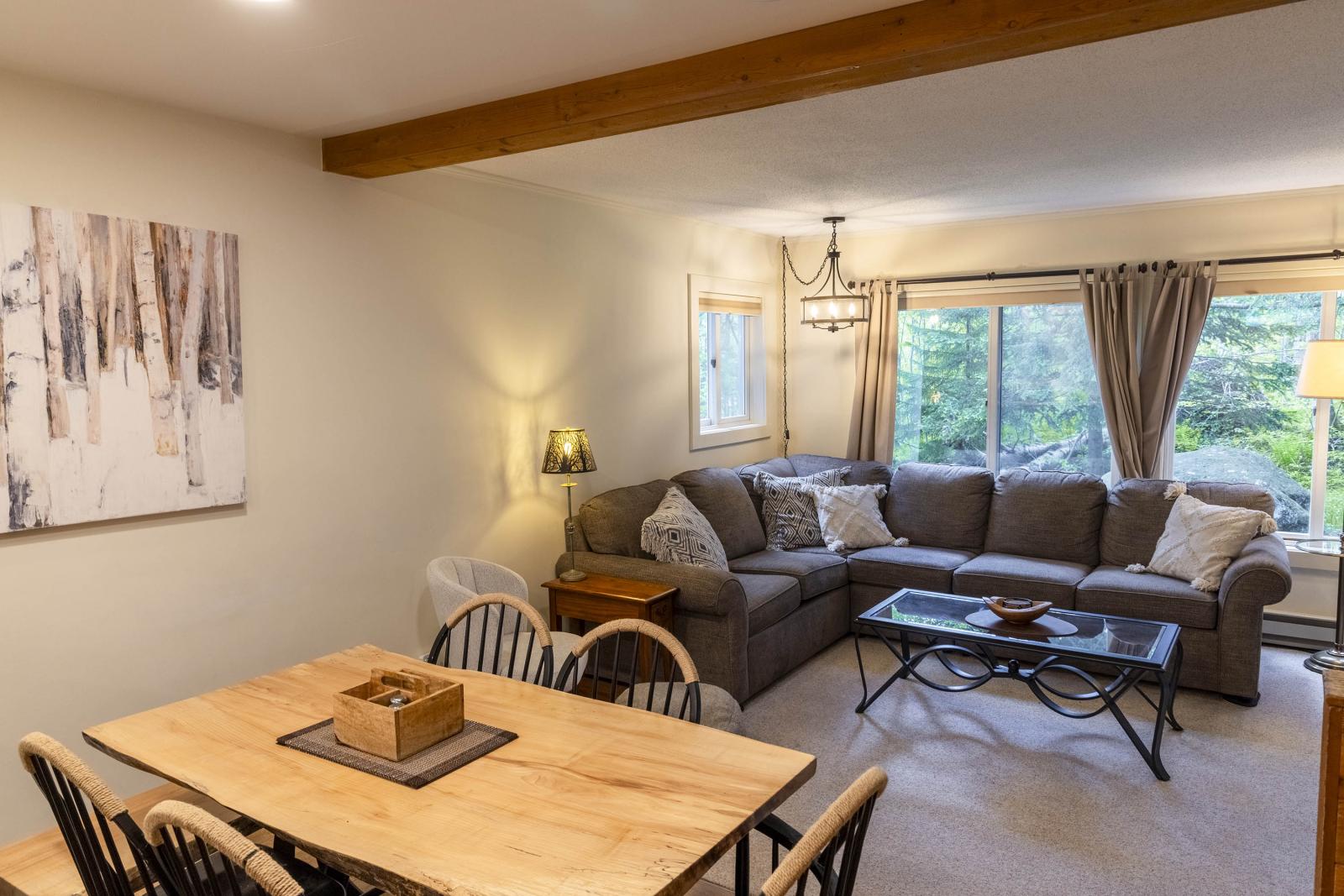 Cozy living room with a sectional sofa, wooden dining table, and large window.