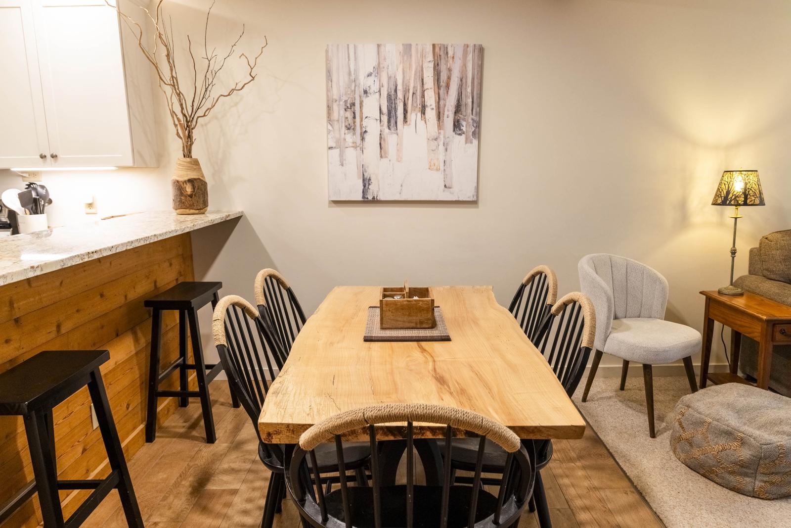 Cozy dining area with a wooden table, black chairs, and warm lighting.