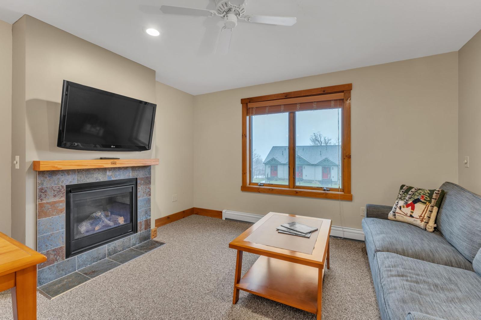 Cozy living room with fireplace, TV, sofa, and a window view.