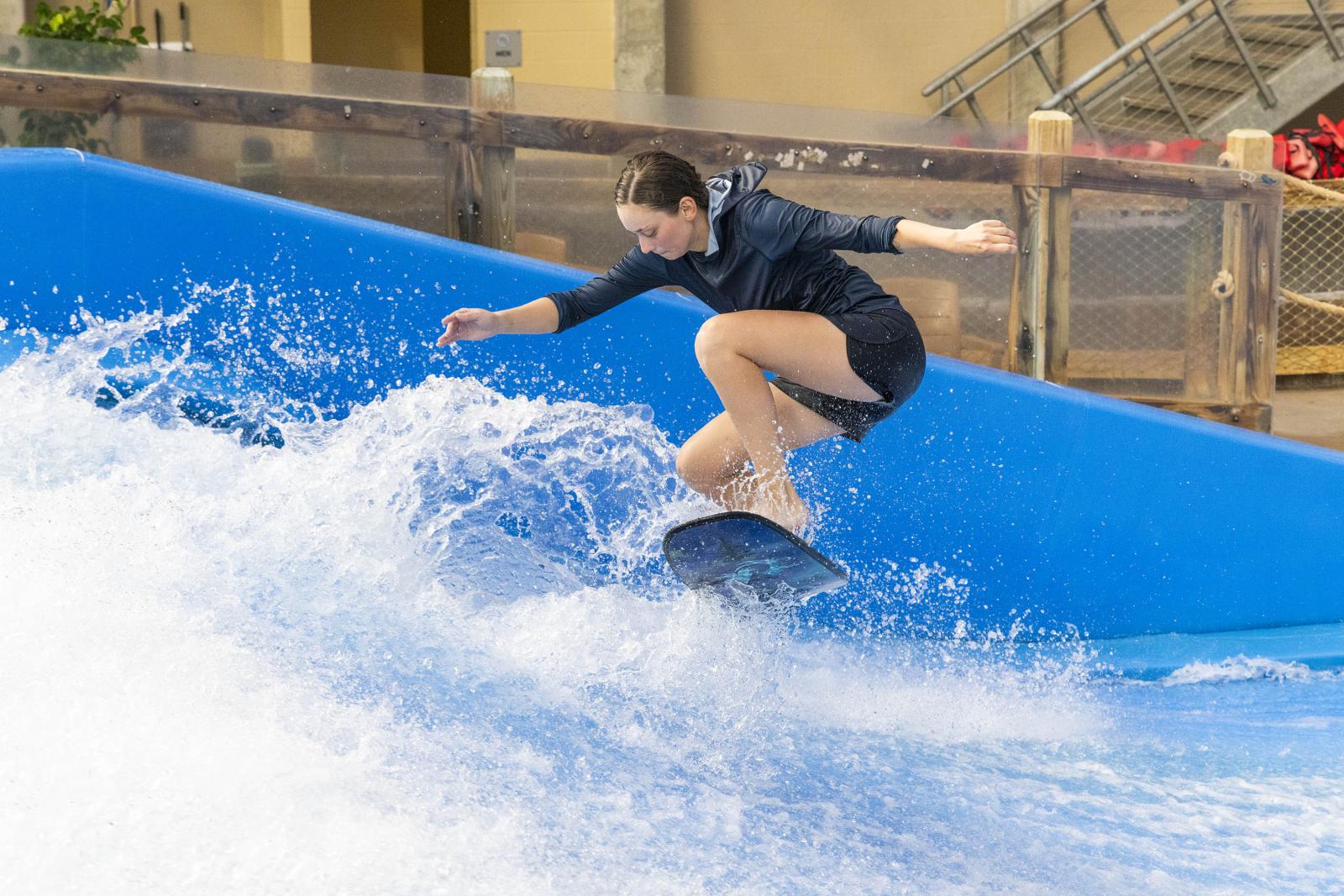 Person surfing on an artificial wave indoors.