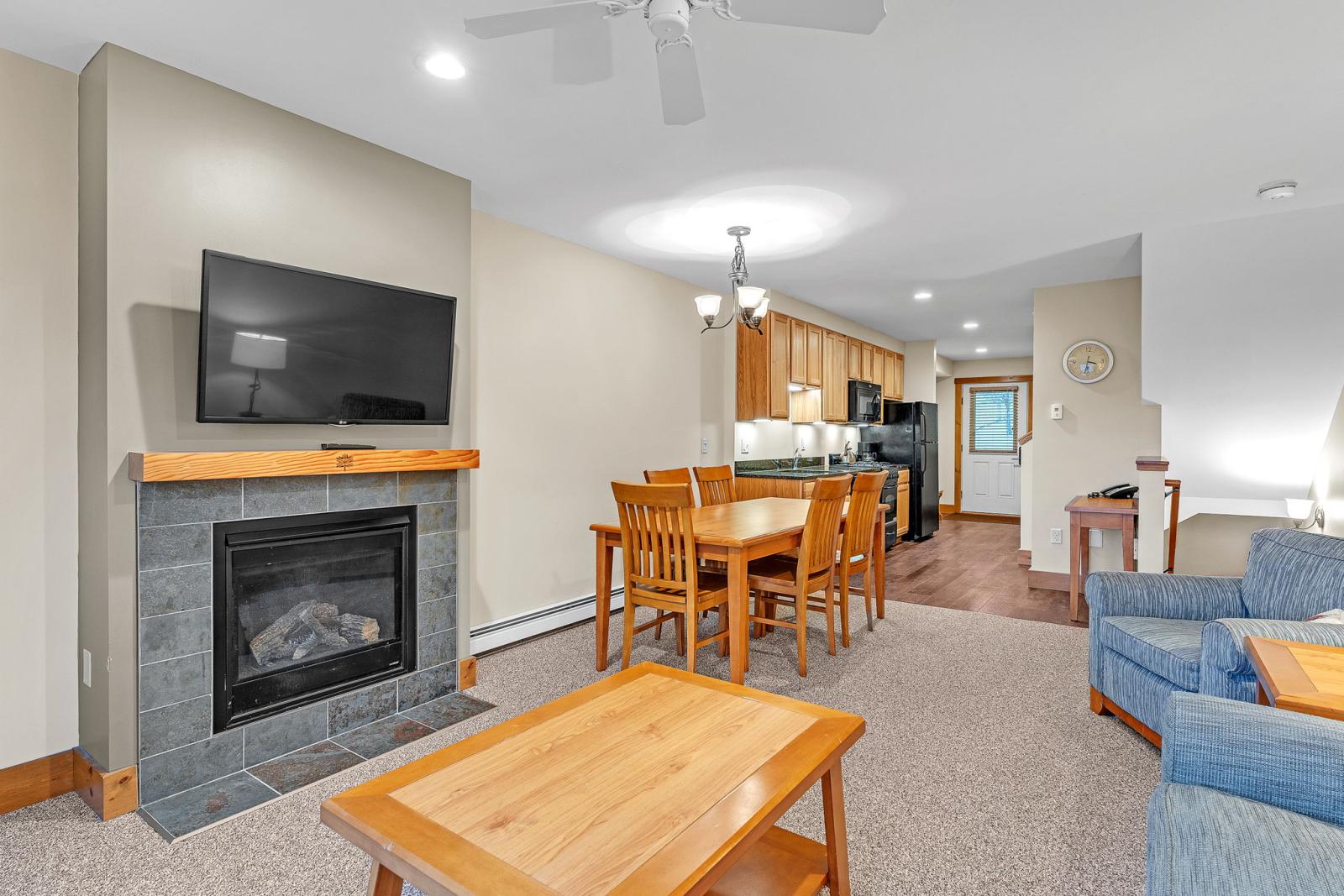 Cozy living room with fireplace, TV, and wooden dining table.