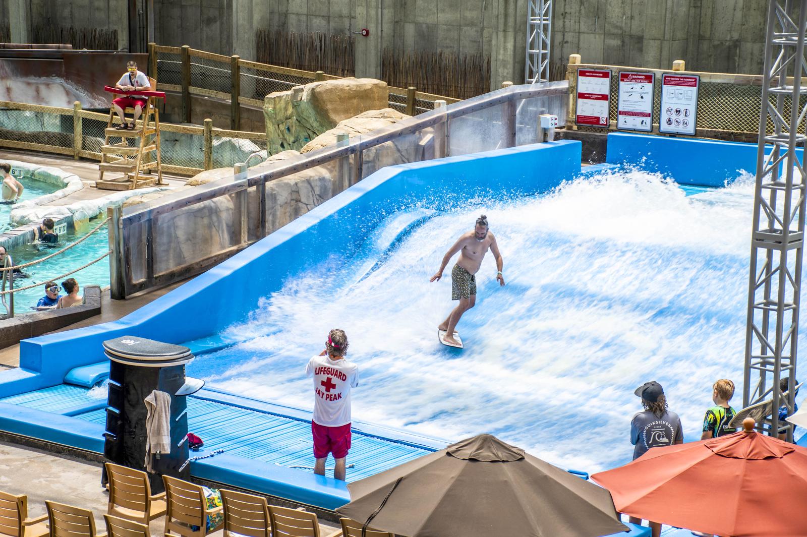 Surfer balances on an artificial wave at a water park.