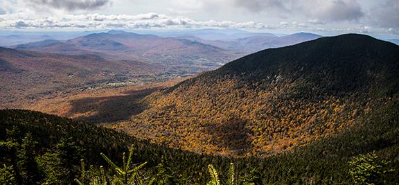 Mountain landscape with autumn foliage, under a cloudy sky.