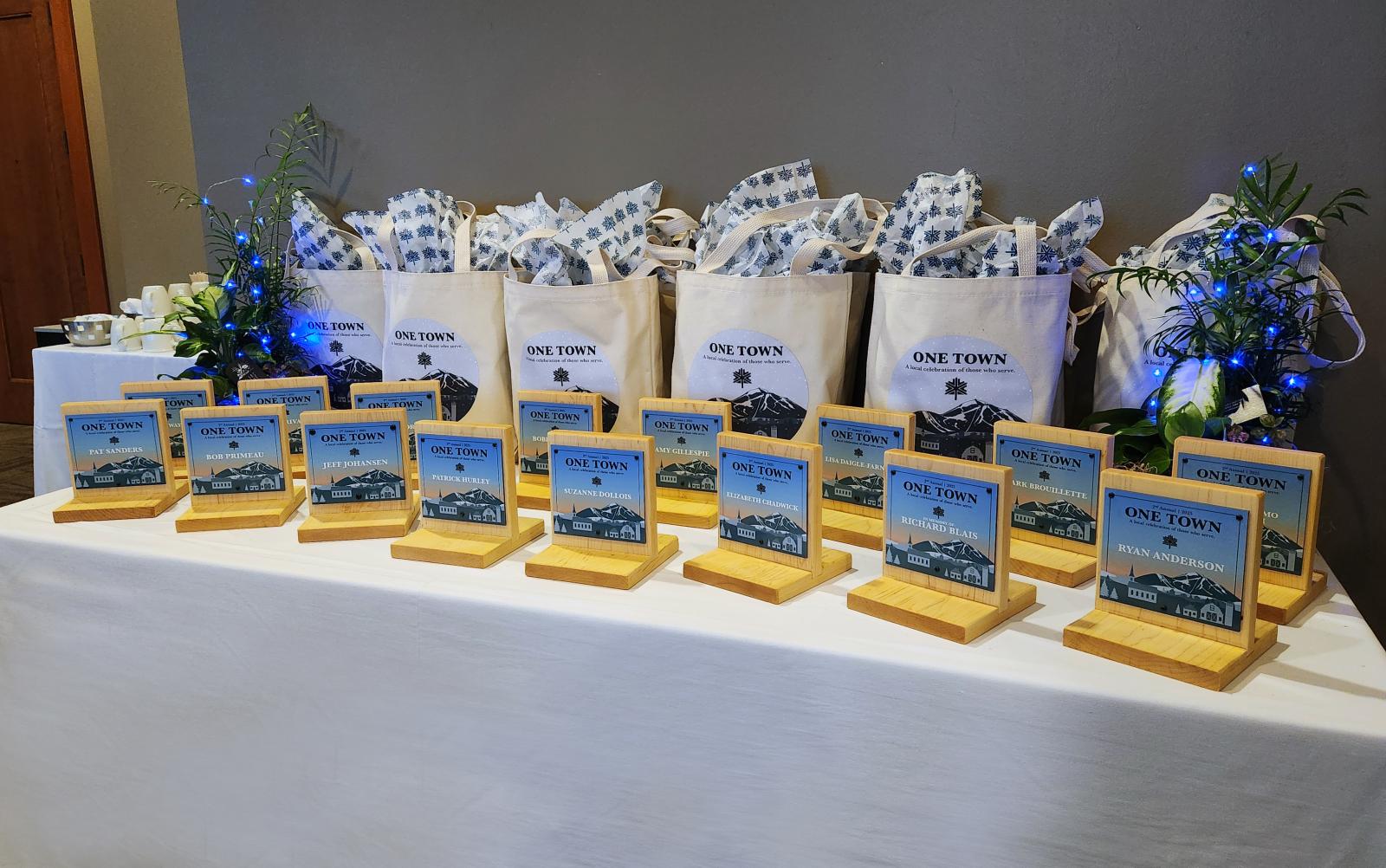 Awards on a table, with gift bags and decorative plants behind.