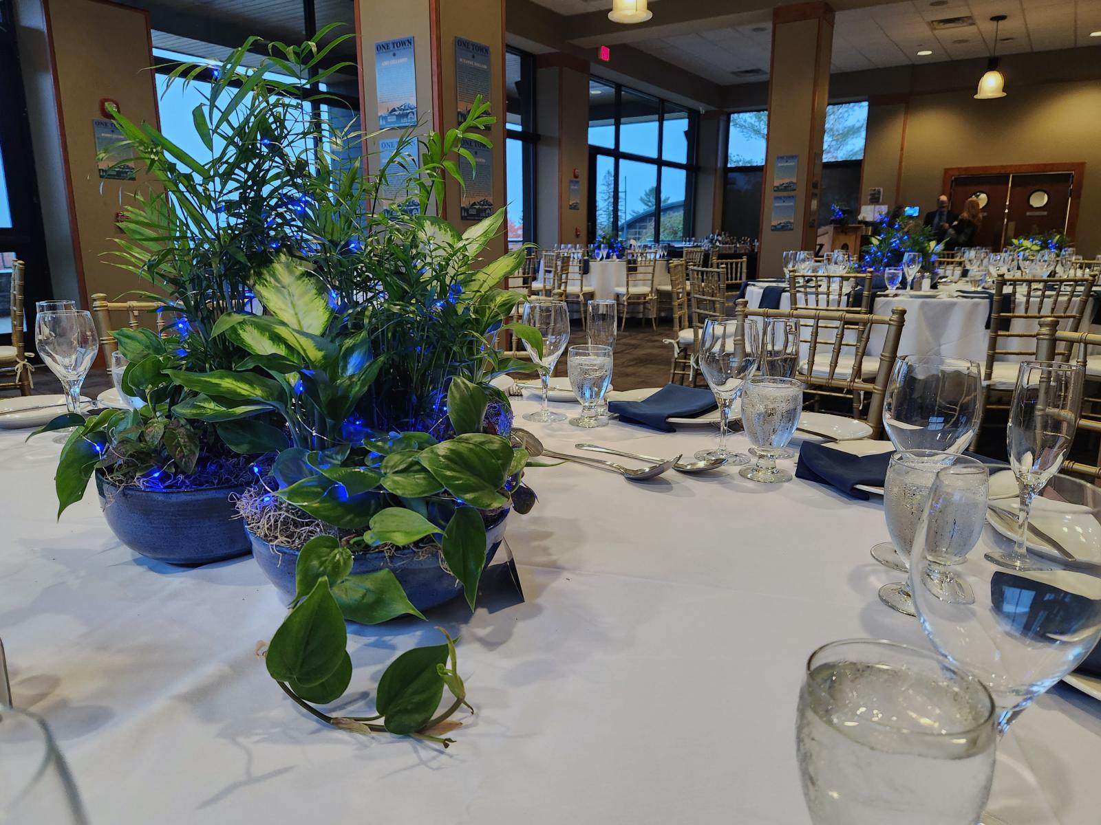 Elegant table setting with green centerpieces and blue accents.