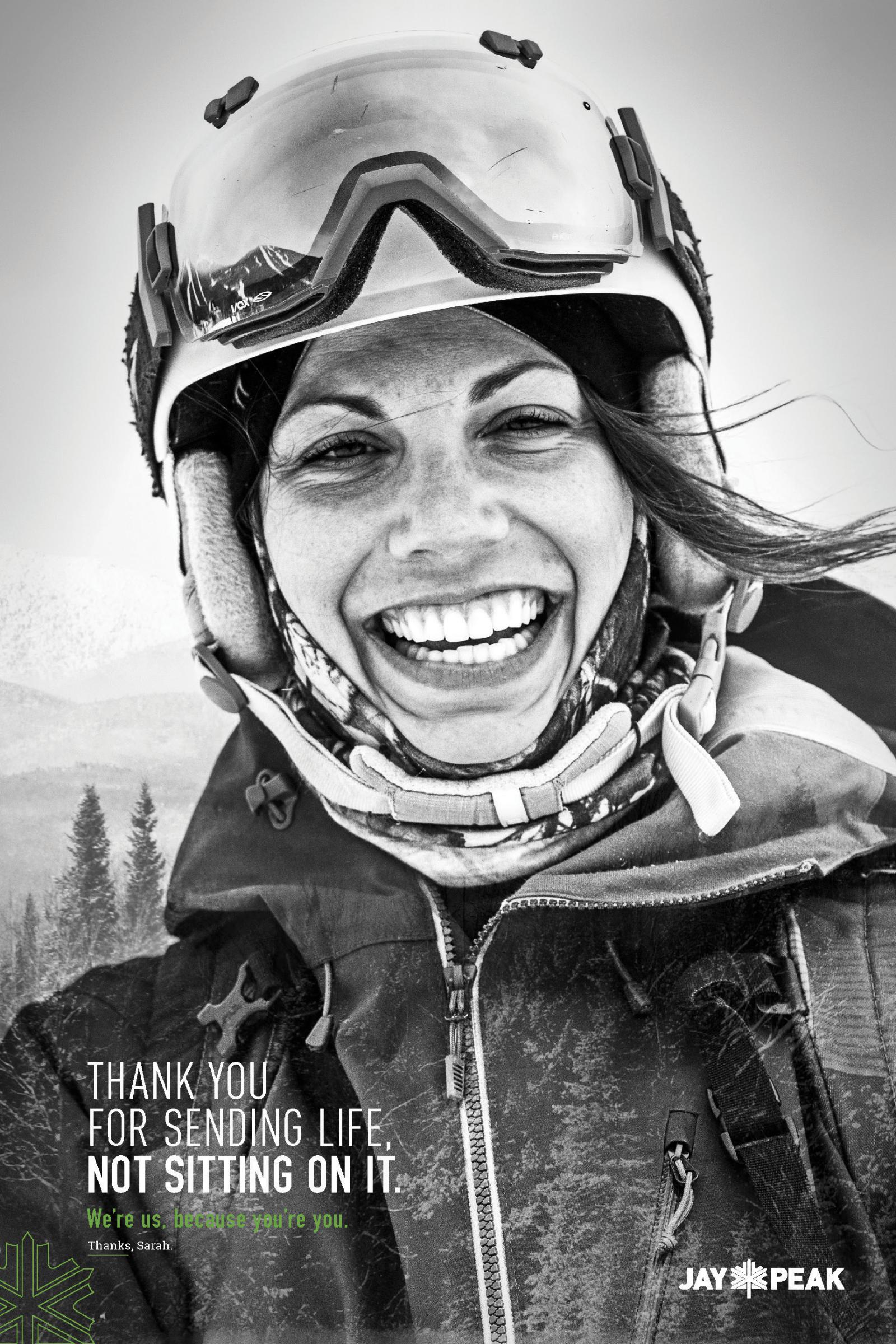Smiling person wearing ski gear in black and white photo.