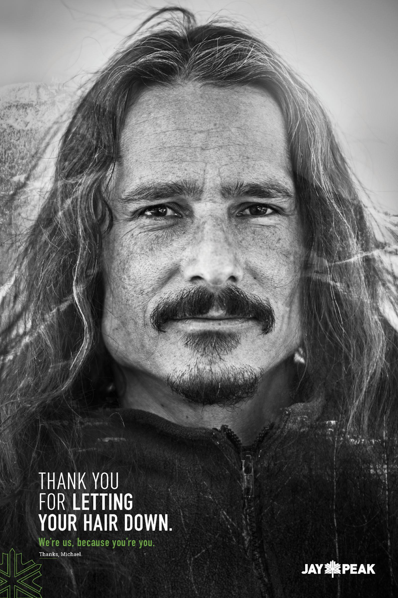 Black and white photo of a man with long hair and a mustache, looking directly at the camera.