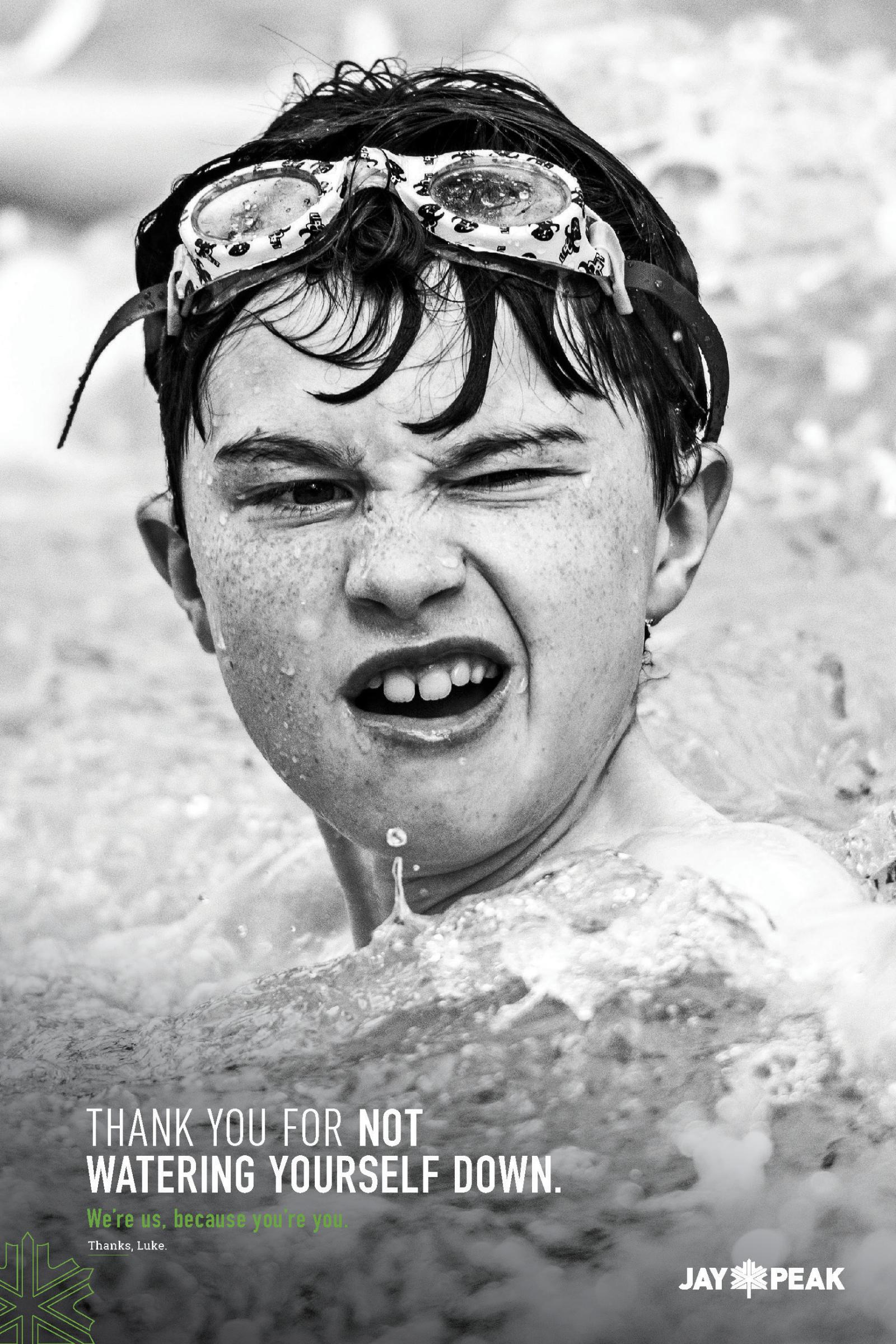 Wet child with goggles in pool, winking and smiling. Black and white photo.