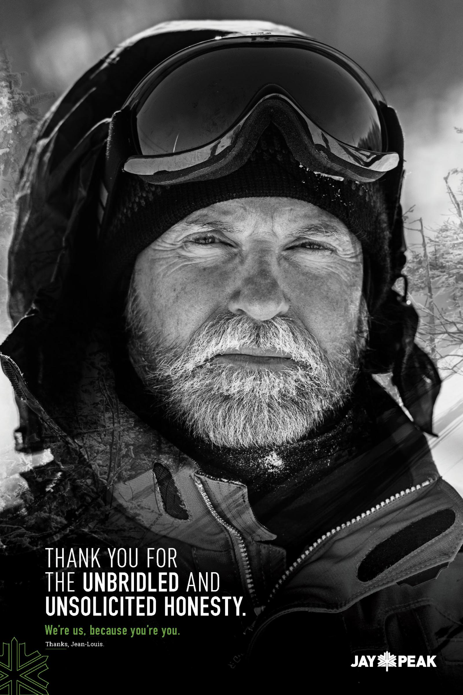Bearded man in winter gear with snow goggles, looking serious. Black and white photo.