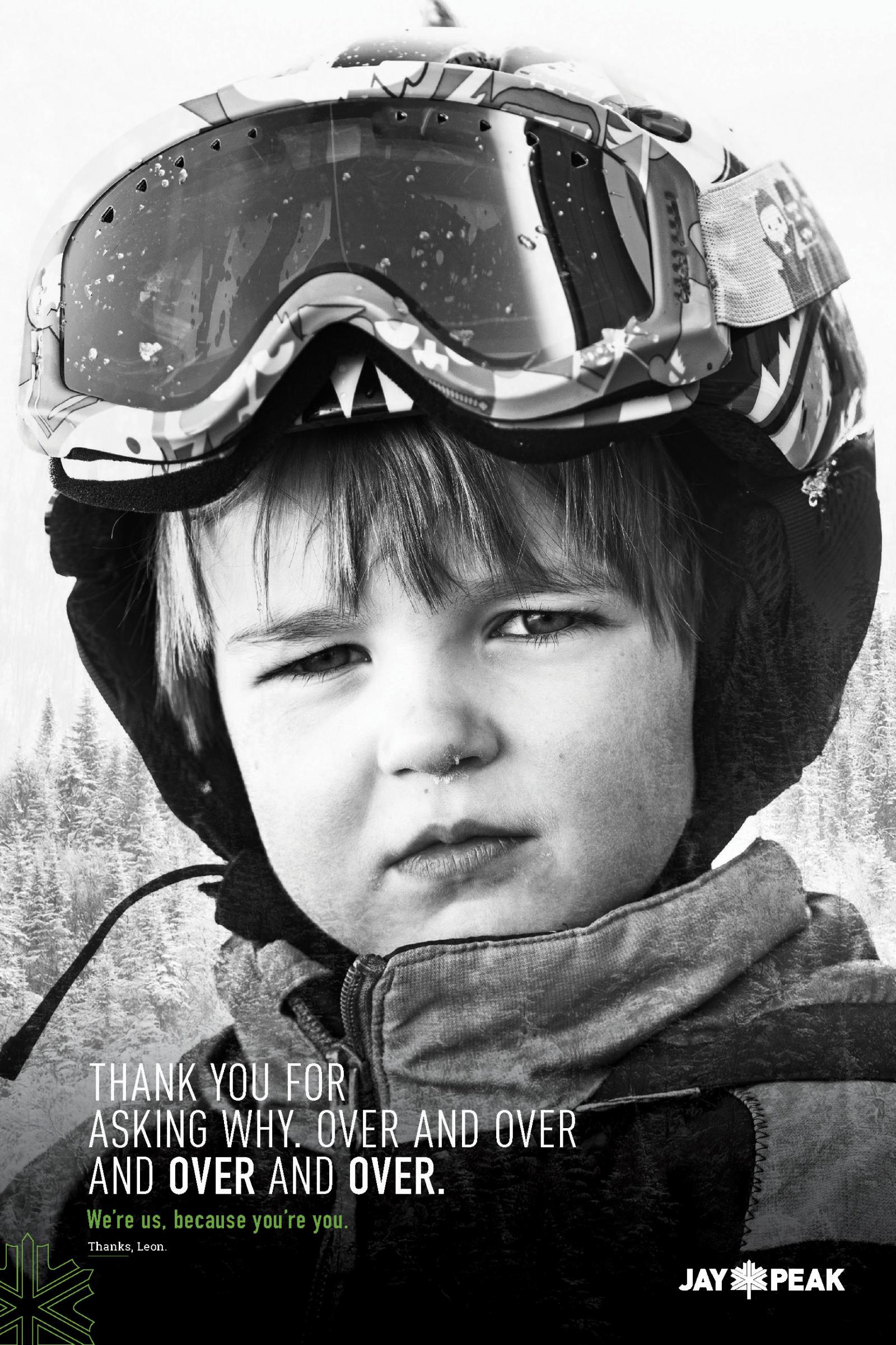 Young child in ski gear, wearing goggles and looking serious in a snowy setting. Black and white.