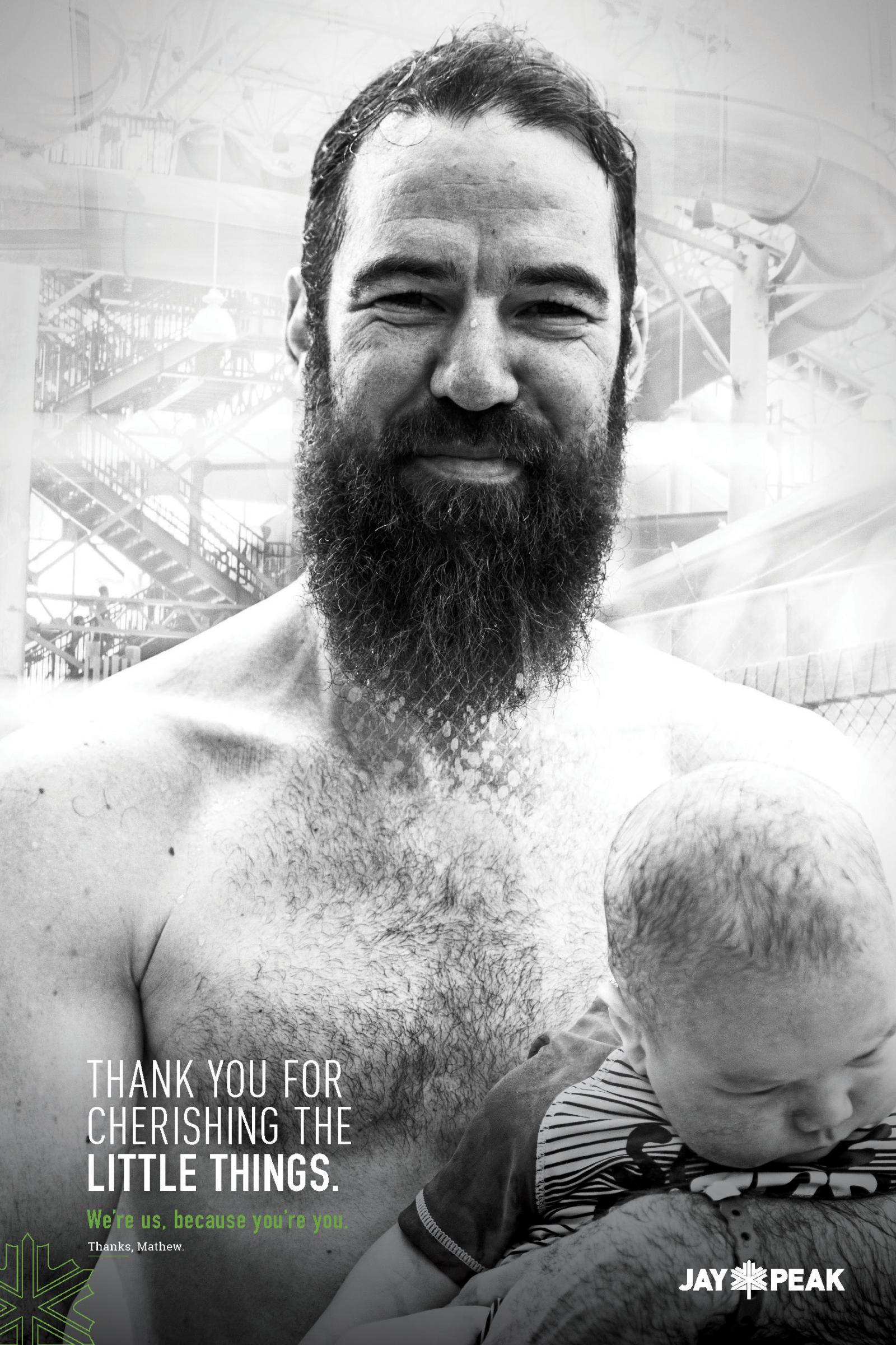 Man with a beard smiling, holding a baby. Black and white photograph.