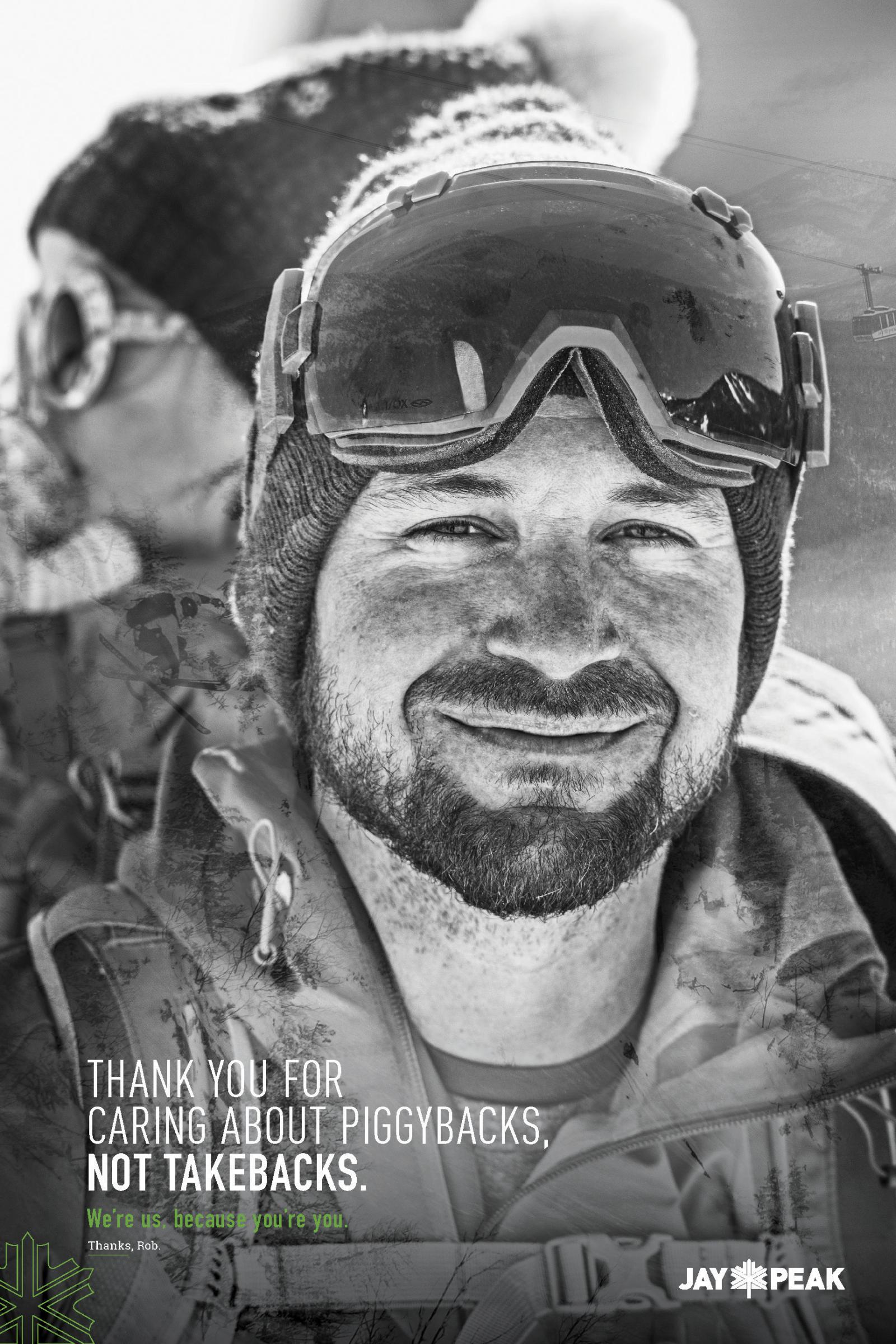 Man in ski gear smiling, snowy background, grayscale photograph.