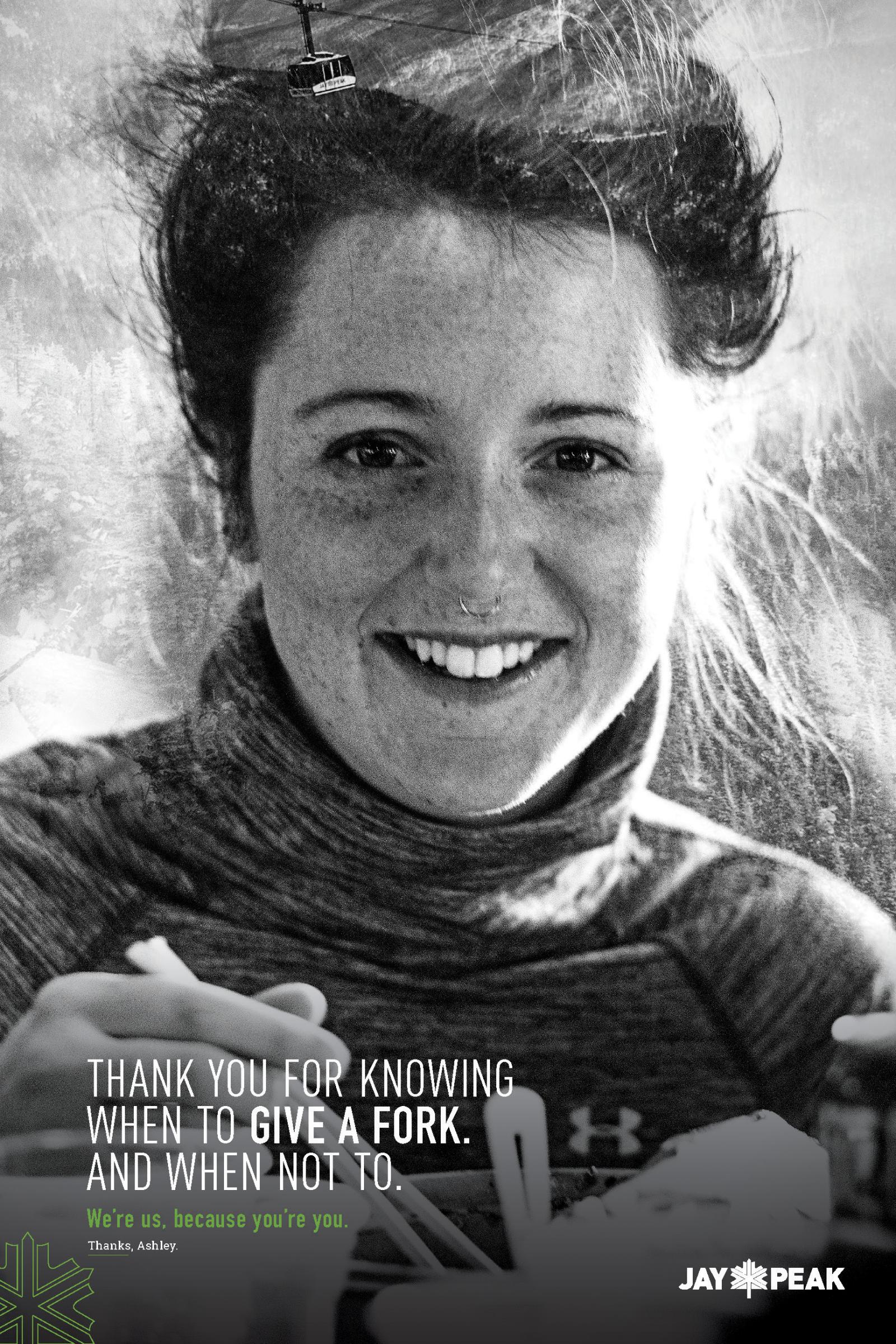 Smiling woman in winter clothing holds a fork, black and white photo.