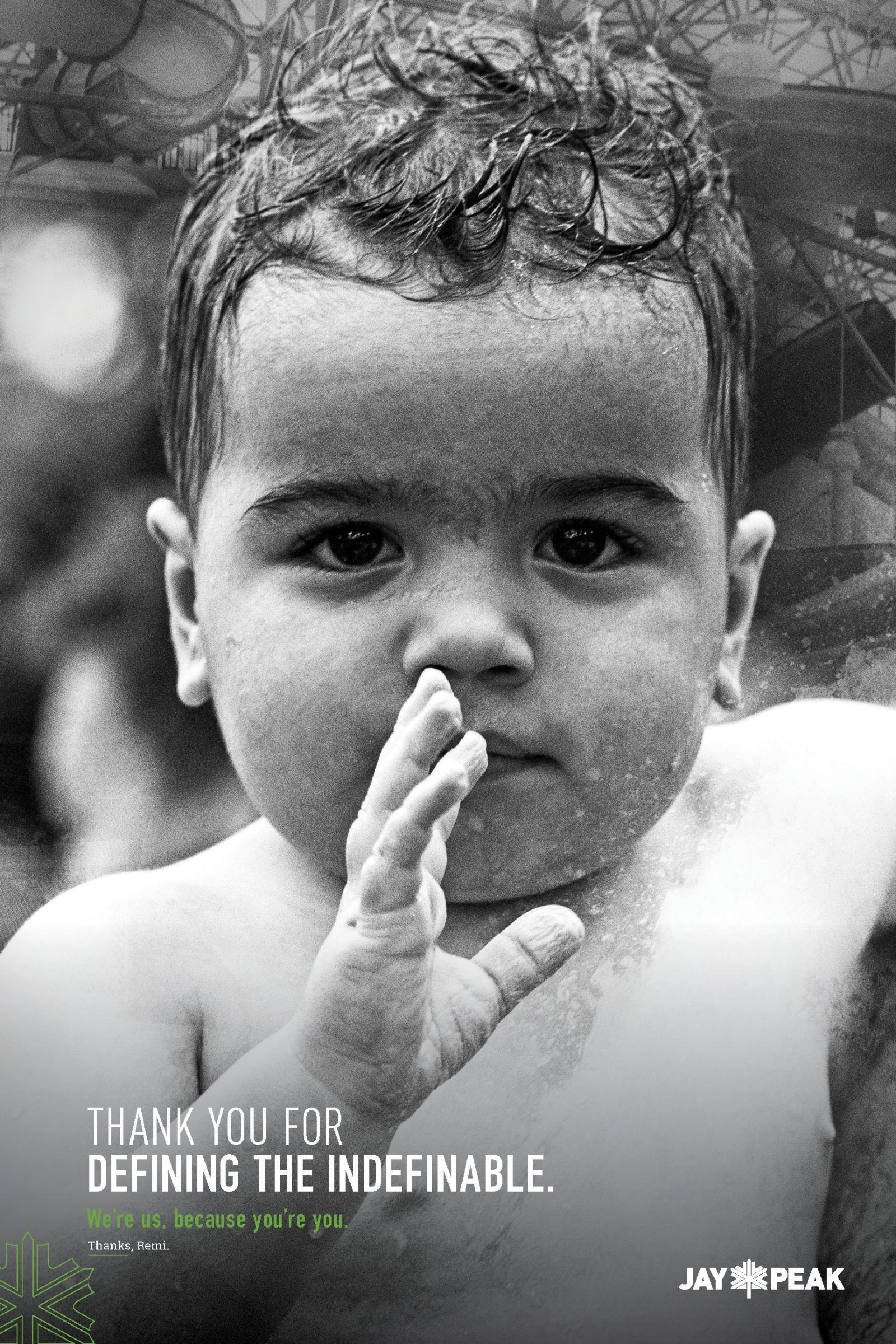 Young child with curly hair and hand near mouth, photographed in black and white.