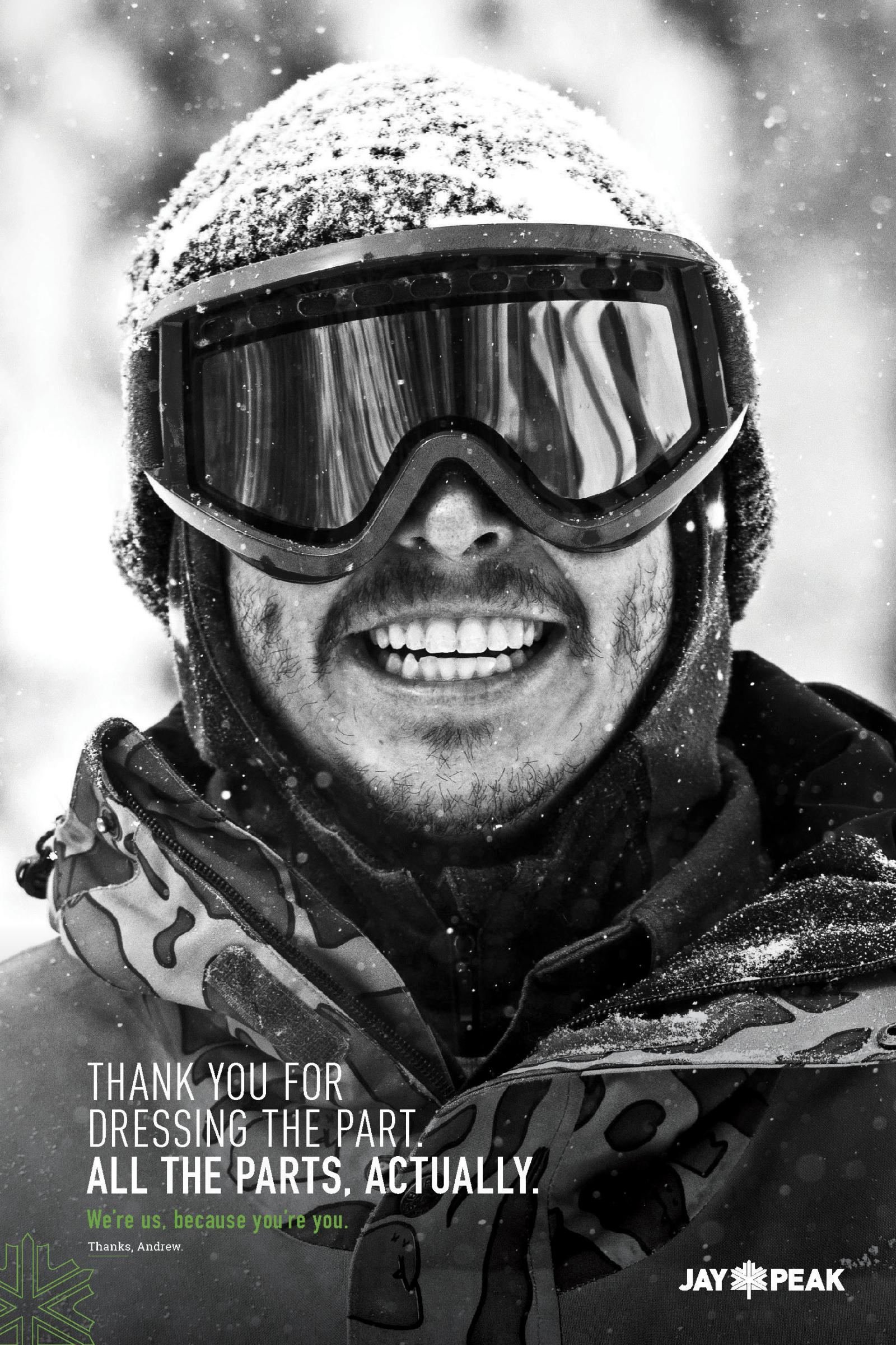Smiling person in ski goggles and winter gear, snow-covered background.