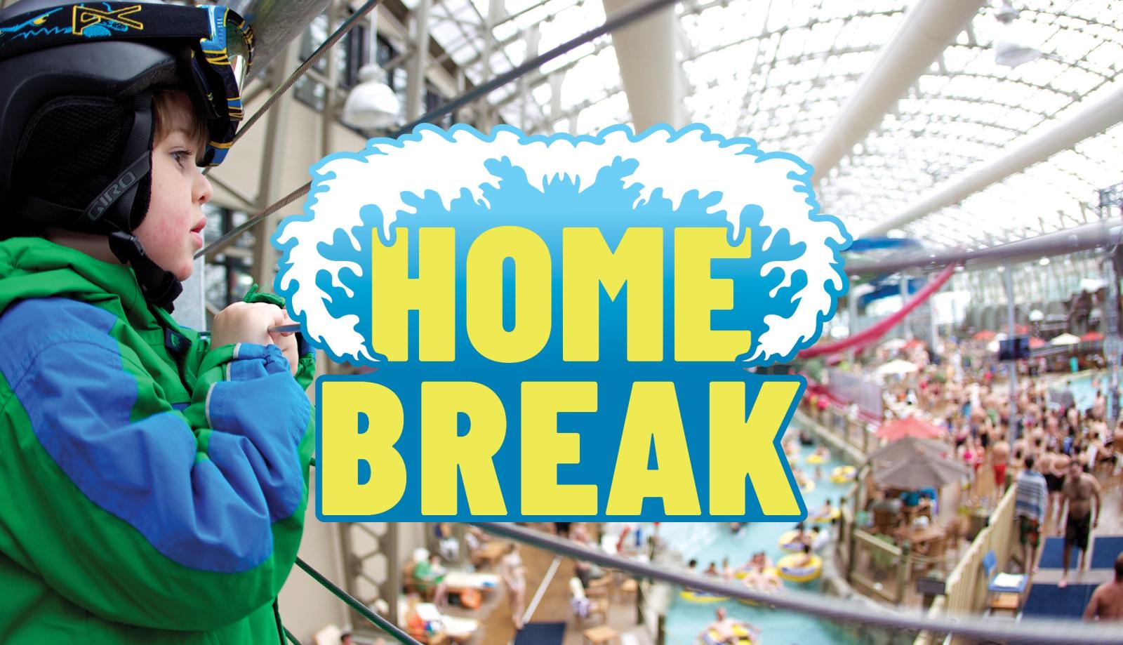 Child in green coat overlooking large indoor water park with slides.