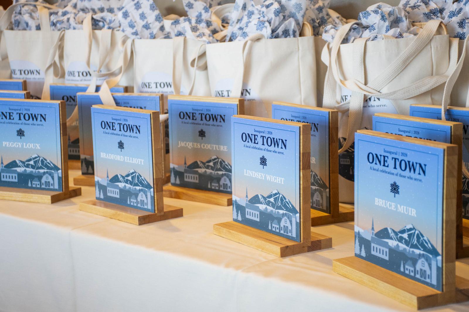 Award plaques on a table, with tote bags in the background.