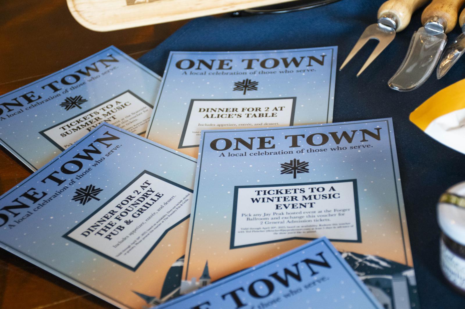Blue event brochures and serving utensils on a table.
