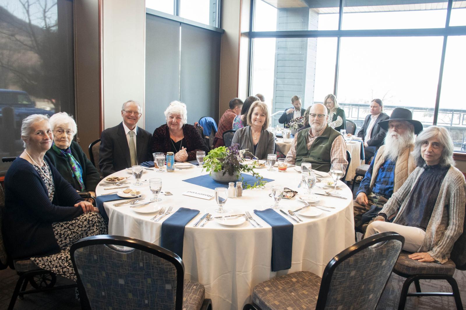 Group seated around a round table, smiling at a formal event.