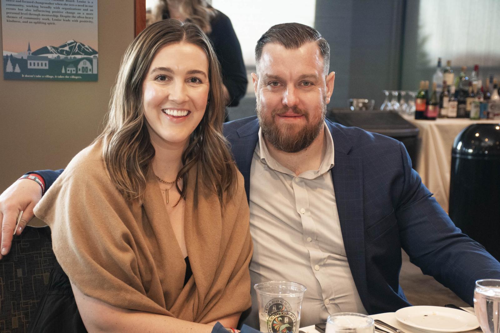 Smiling couple sitting together at a table in a restaurant setting.