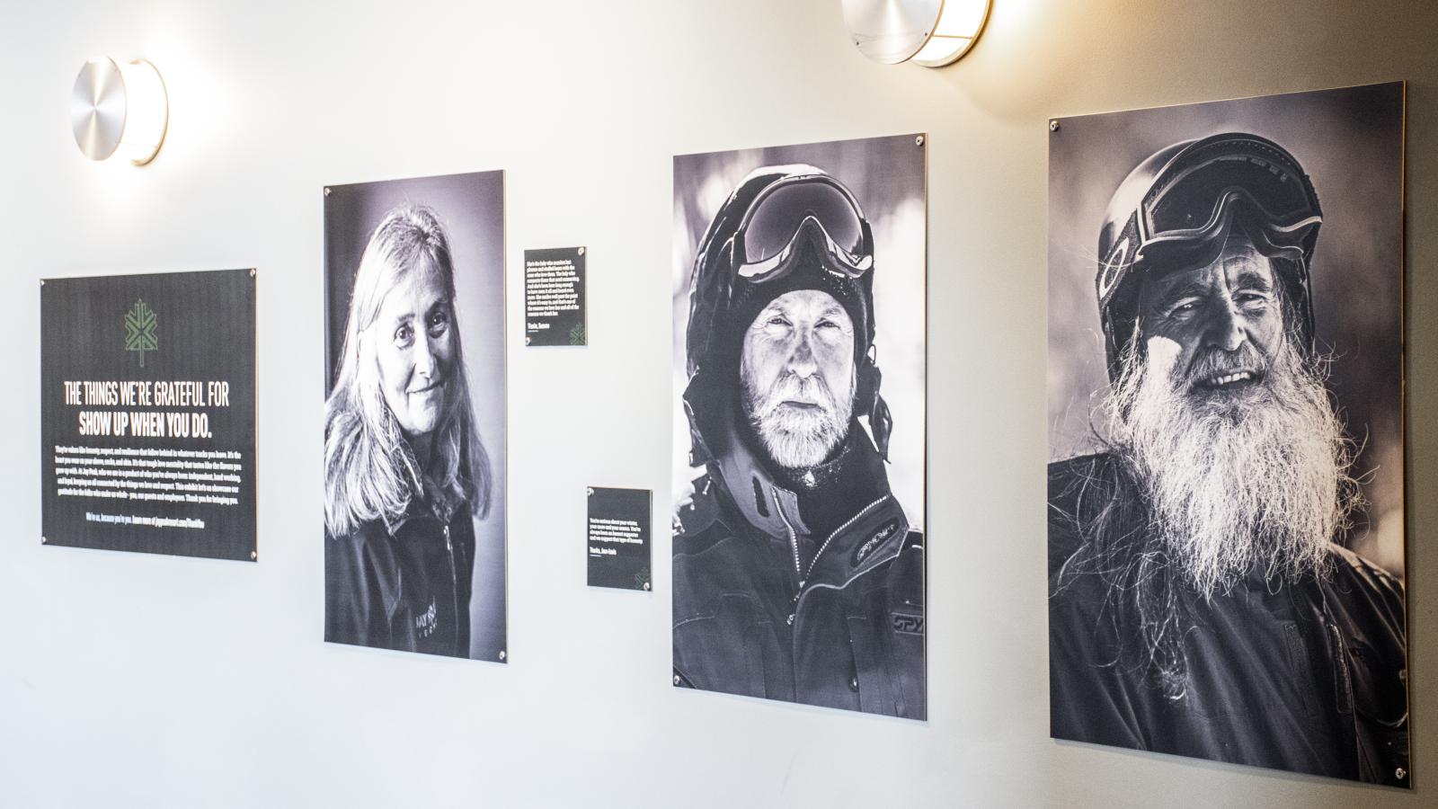 Black and white portraits of three older individuals on a wall, softly lit.