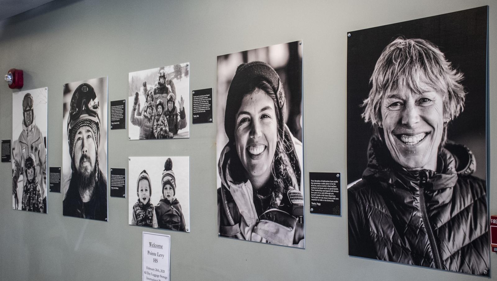 Black and white photo exhibit on a wall, featuring smiling portraits.
