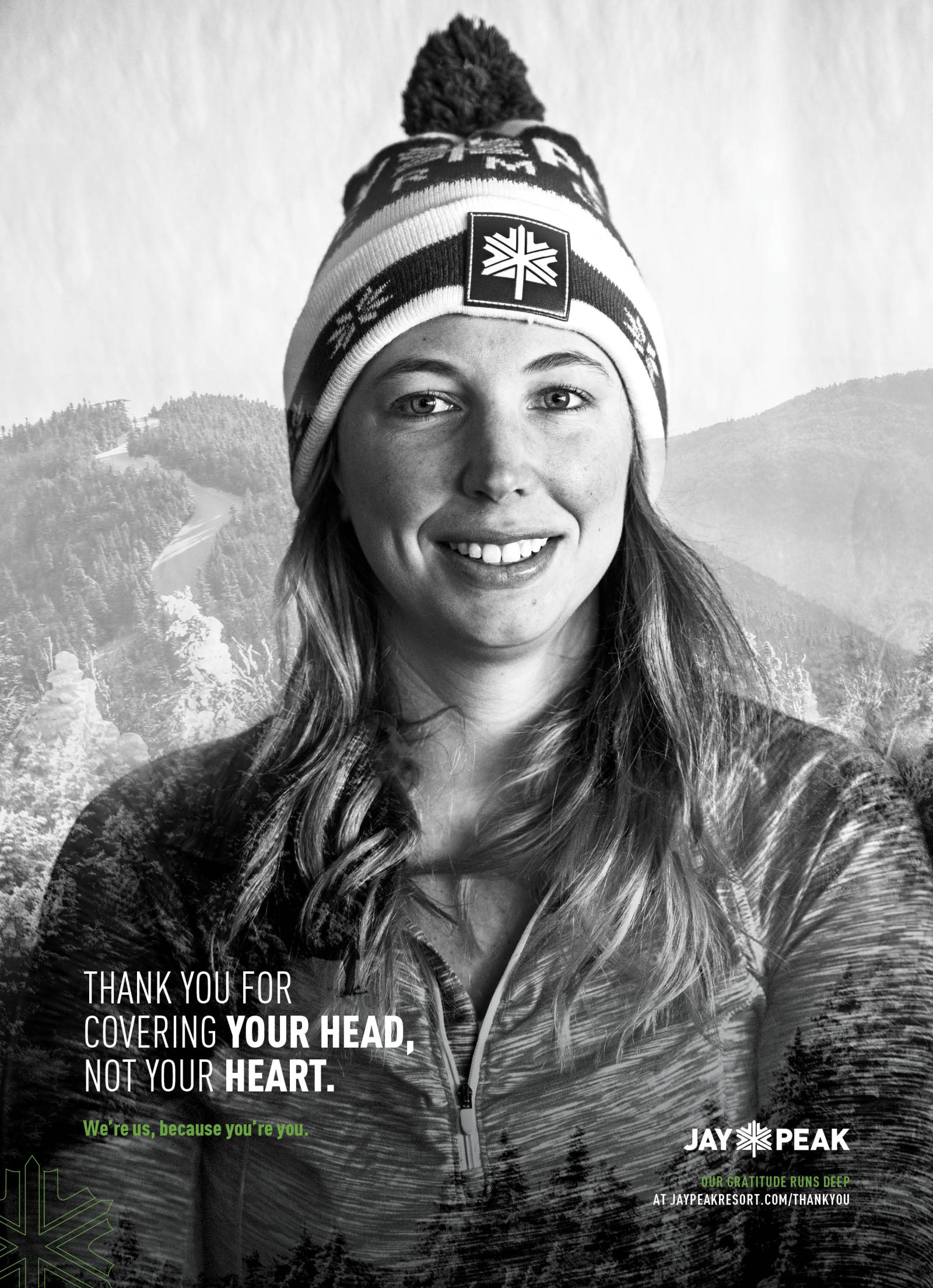 Black and white photo of a smiling woman in a winter hat against a mountain backdrop.