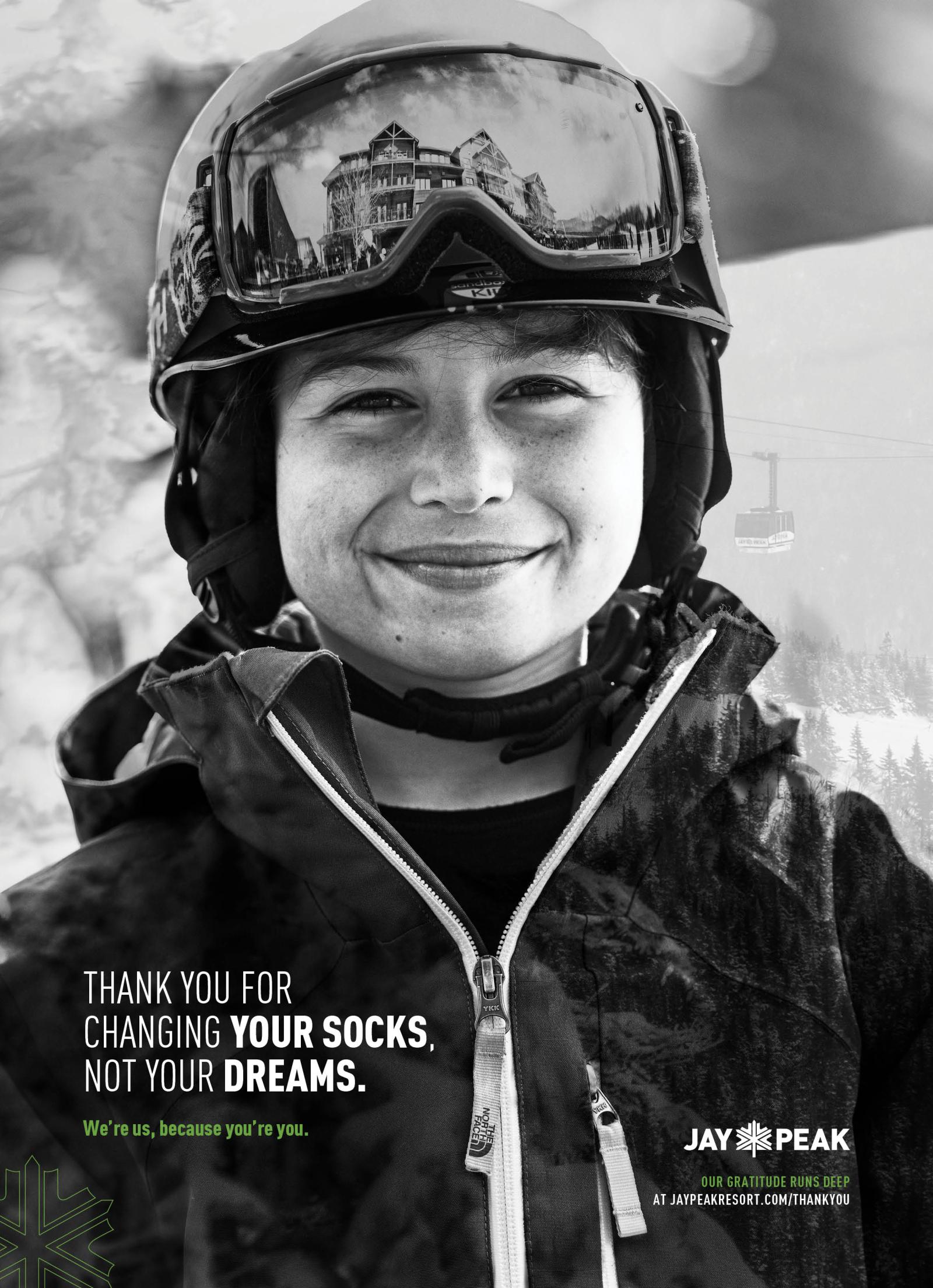 Smiling skier wearing a helmet and goggles in a snowy setting. Black and white photograph.